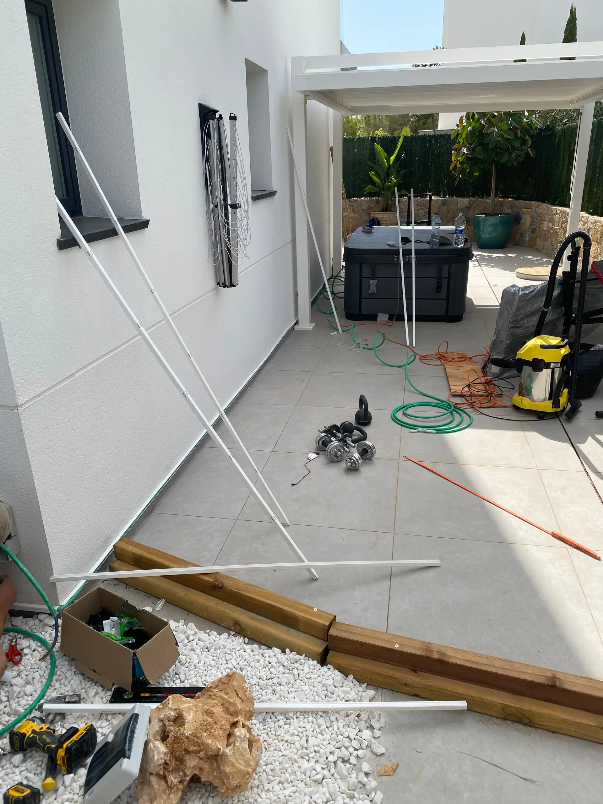 Terrace mid-works with white profiles leaning on the wall, the crated spa and tools spread around