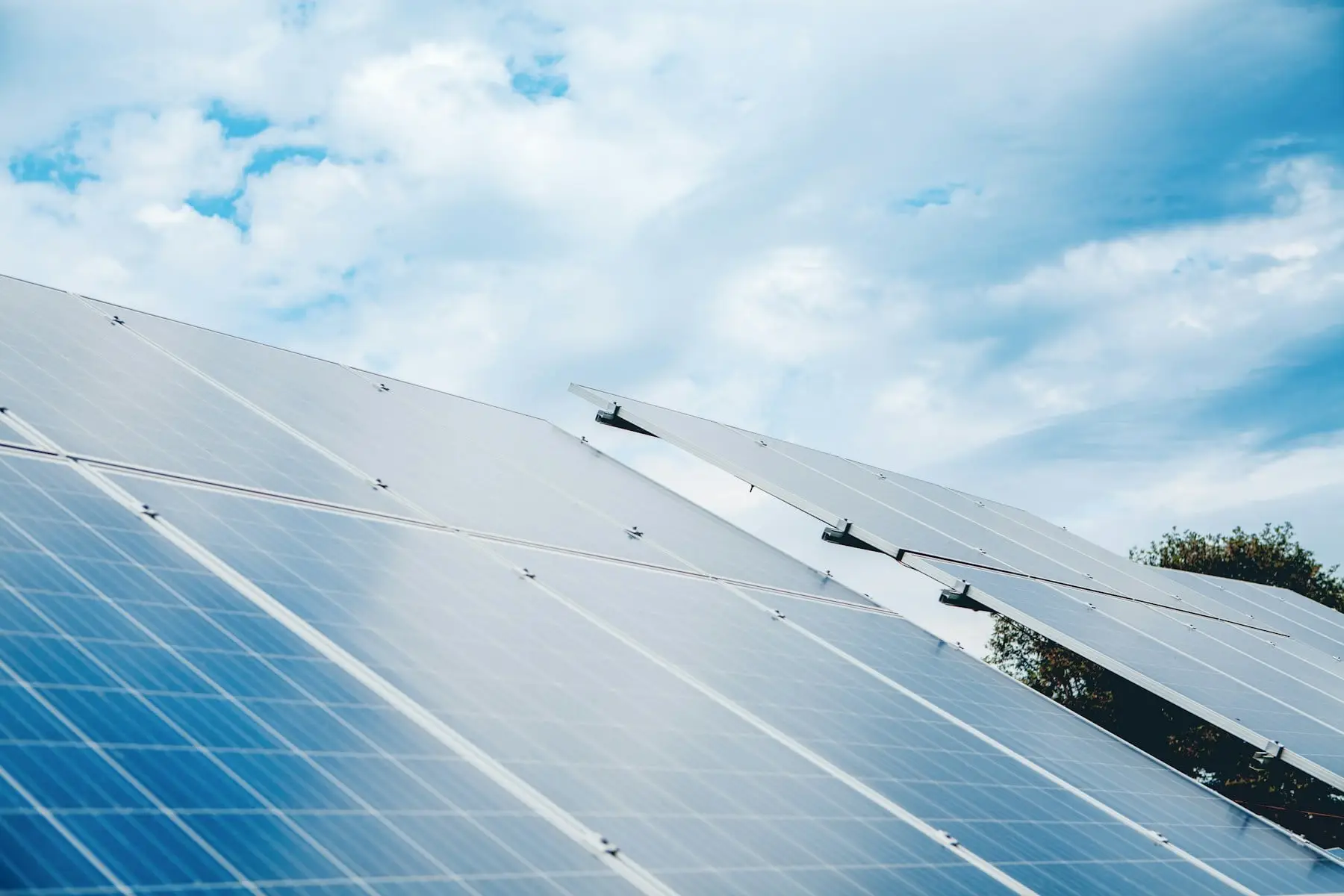 Rows of blue solar panels tilted towards a cloudy sky
