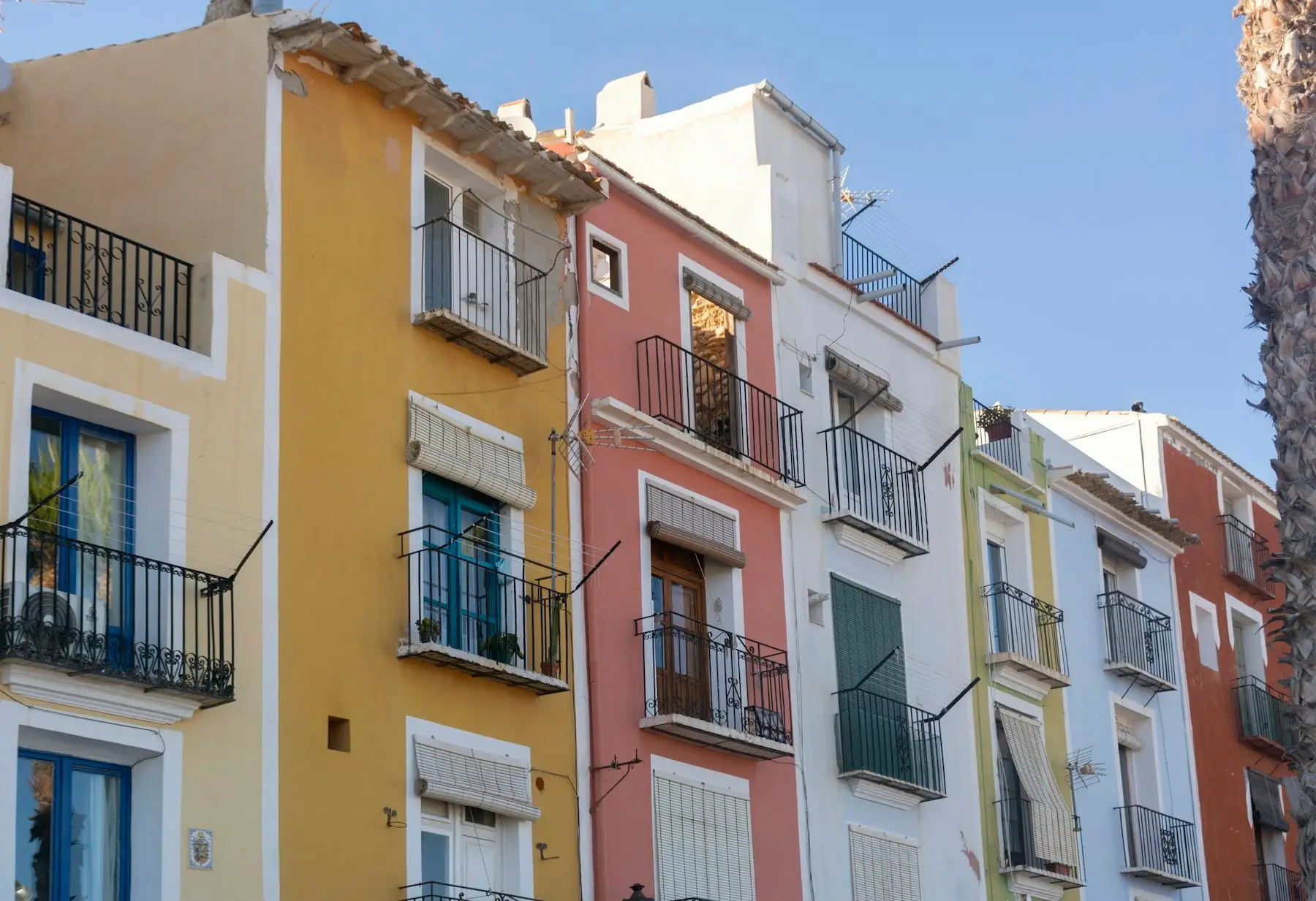 The painted houses of Villajoyosa old town: yellow, pink and white façades with iron balconies.
