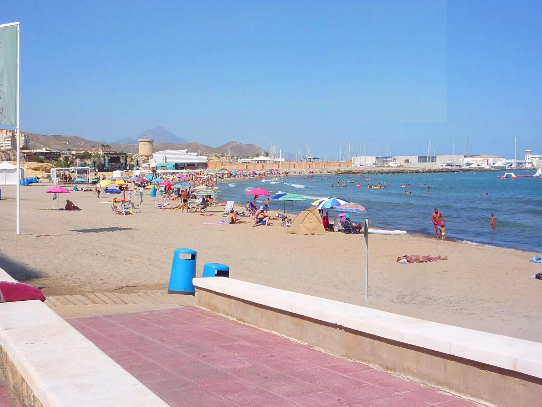 The beach at El Campello in summer, with the Illeta watchtower and the marina behind it.